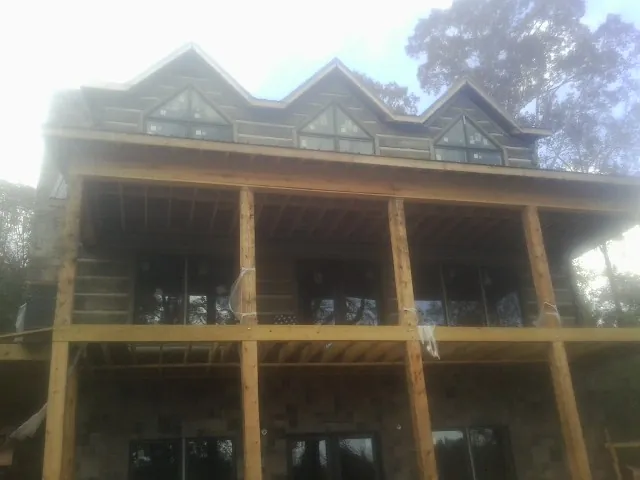 Dormers and porch framing on a large log home under construction — Roof Coating work by our crew in New Ulm