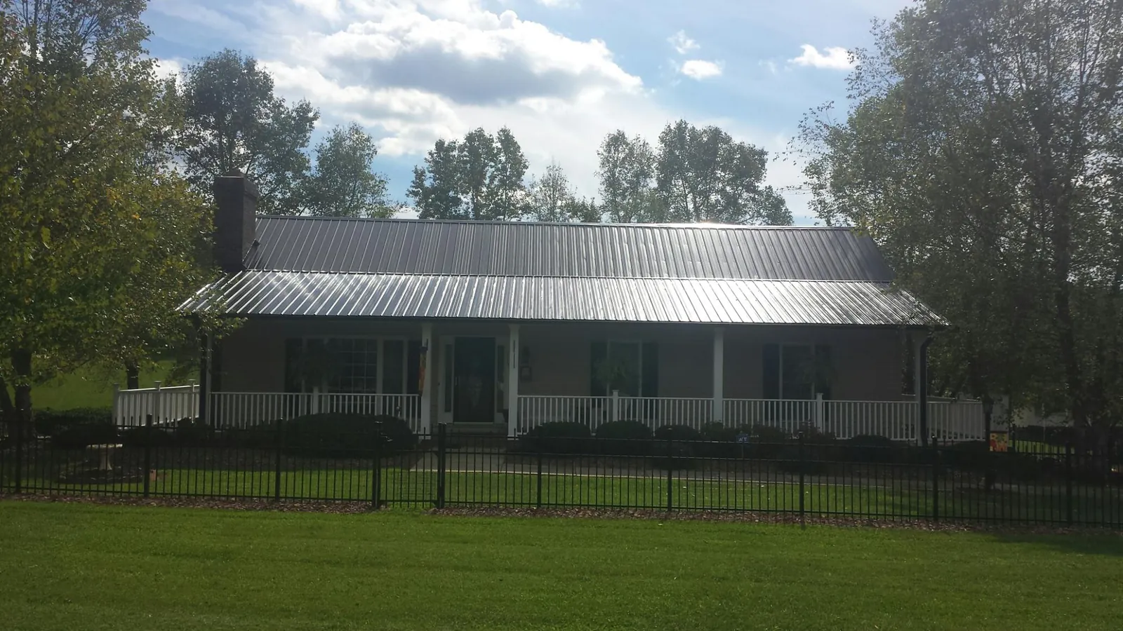 Gray metal roof on a brick ranch with a full width front porch — Gutter Guard Installation work by our crew in New Ulm